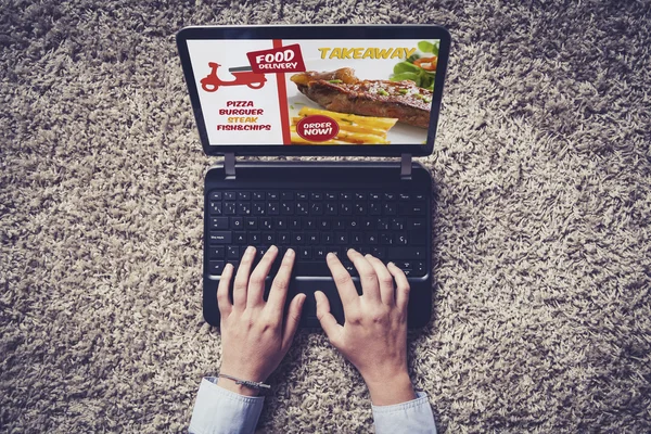 Pohled shora notebooku s jídlo odnést na obrazovce. Ruce na klávesnici. — Stock fotografie