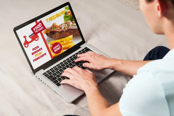 Muž objednávání odnést jídlo po internetu s přenosným počítačem zatímco sedí doma. — Stock fotografie