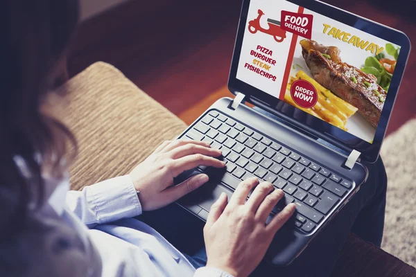 Žena objednávání odnést jídlo po internetu s přenosným počítačem zatímco sedí na gauči doma. — Stock fotografie