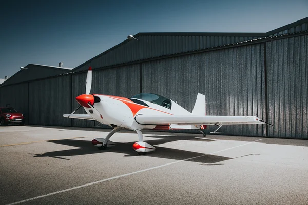 Weißes und rotes Kleinflugzeug an der Hangartür. — Stockfoto