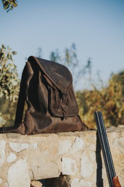 Deri çanta içinde kırsal taştan bir duvar. Avcılık kavramı.