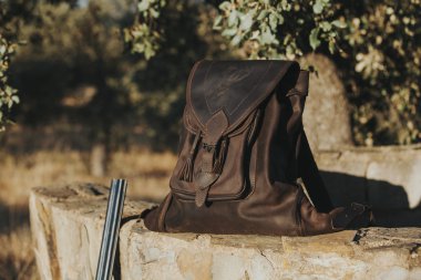 Deri çanta içinde kırsal taştan bir duvar. Avcılık kavramı.