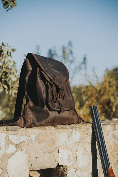 Leather bag in a stone wall at the countryside. Hunting concept. — Stock Photo, Image