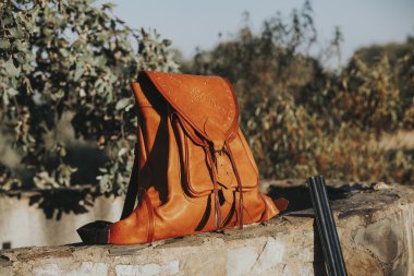 Deri çanta içinde kırsal taştan bir duvar. Avcılık kavramı.