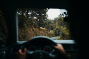 Sürücü bakış açısından ıslak yol, dağlarda araba sürerken görülüyor..