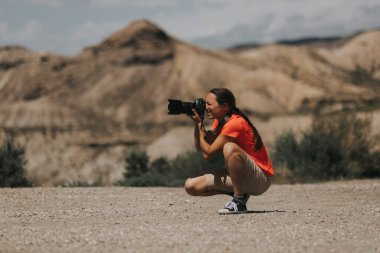 Spor fotoğrafçısı kadın, güneşli bir günde Tabernas Çölü 'nde turuncu bir tişörtle fotoğraf çekiyor..