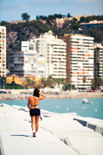 Jonge vrouw lopen aan de rand van de kust, tijdens sport sessie — Stockfoto