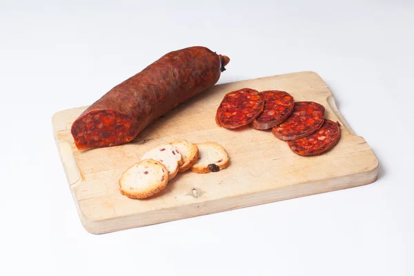 Spaanse chorizo gesneden op een houten bord. — Stockfoto