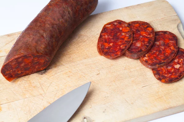 Chorizo slices and knife over a wood board. — Stock Photo, Image