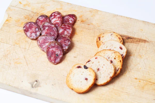 Segmenten van chorizo en brood over houten bord. Close-up. — Stockfoto
