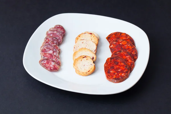 Spaanse chorizo tapa over zwarte tabel. — Stockfoto