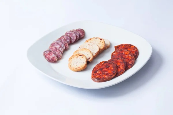 Hiszpański tapa plasterki chorizo w biały danie. — Zdjęcie stockowe