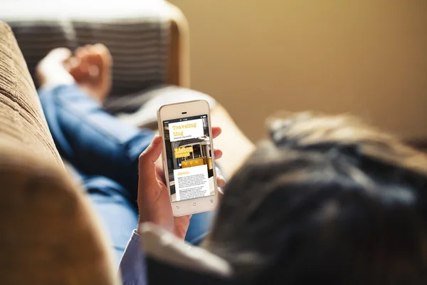 Kvinna läser hennes mobiltelefon, reser blogg på skärmen. — Stockfoto