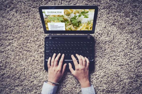 Manos de mujer escribiendo en un portátil. Blog de cocina en la pantalla . — Foto de Stock