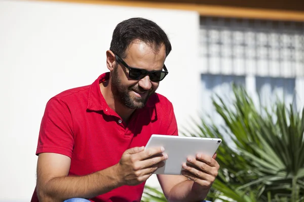 Man using tablet sitting in a bench. — Stock Photo, Image