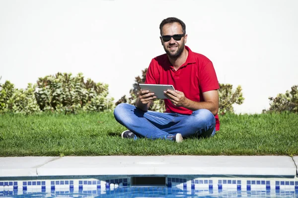 Man sitting on the grass, using a tablet. — Stock Photo, Image