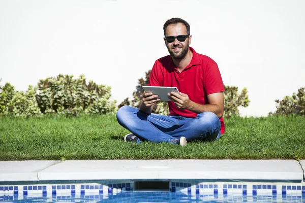 Mann sitzt im Gras und benutzt Tablette. — Stockfoto