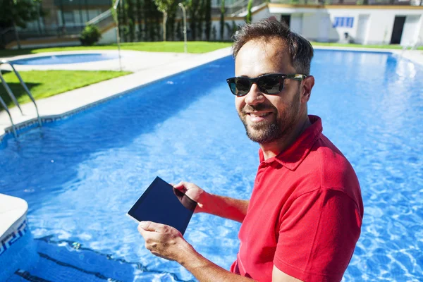 Hombre usando una tableta en la piscina . — Foto de Stock