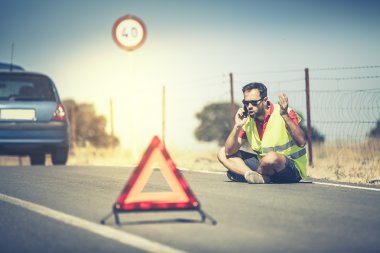 Kızgın adam yolda oturan bir araba arıza sonra telefonla konuşuyor.