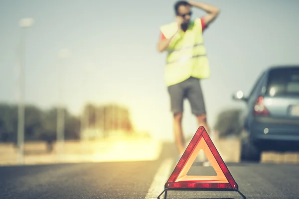 Triangolo di emergenza con uomo e auto sullo sfondo . — Foto Stock