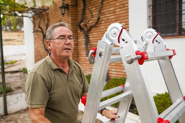 Uomo anziano che sale su una scala. Lavori in giardino . — Foto Stock