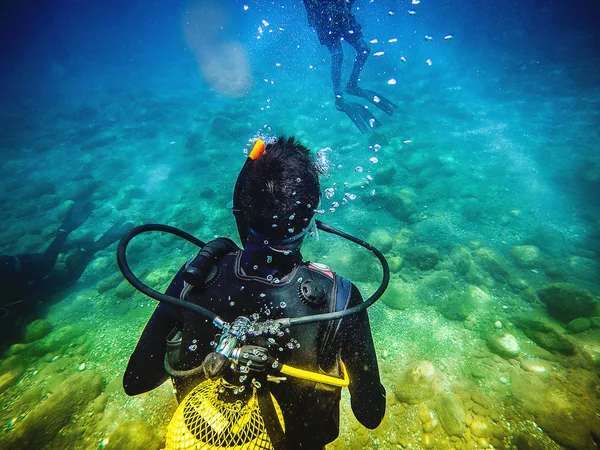 One diver back to camera, looking to another diver in the sea. — Stock Photo, Image