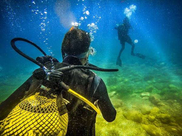 Plongeur de retour à la caméra, regardant vers un autre plongeur dans la mer . — Photo