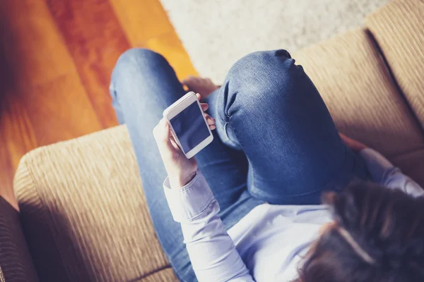 Bir kız bir kanepede otururken bir telefon okuma havadan görünümü. — Stok fotoğraf
