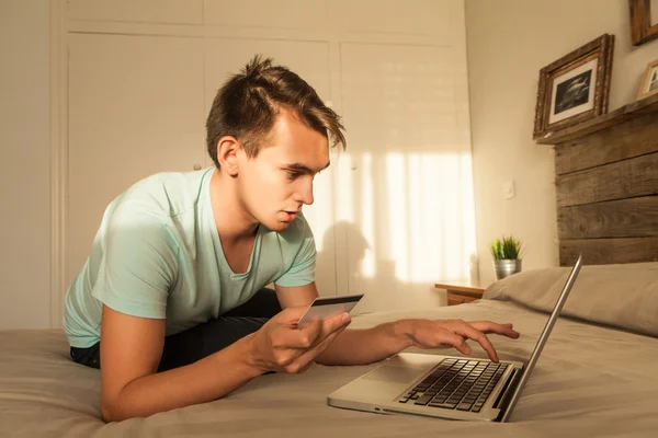 Junger Mann kauft im Internet ein und bezahlt mit Kreditkarte. — Stockfoto