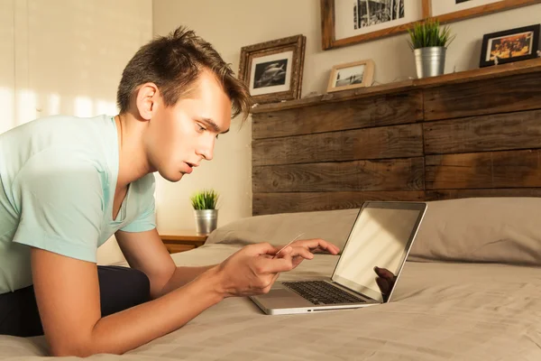 Junger Mann kauft im Internet ein und bezahlt mit Kreditkarte. — Stockfoto