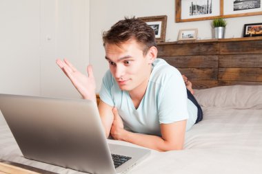 Genç öğrenci evde video konferans için bir dizüstü bilgisayar kullanarak.