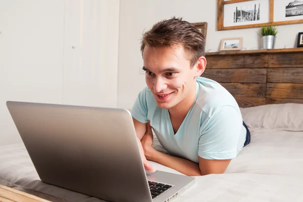 Sonriendo joven estudiante usando el ordenador portátil en casa . — Foto de Stock