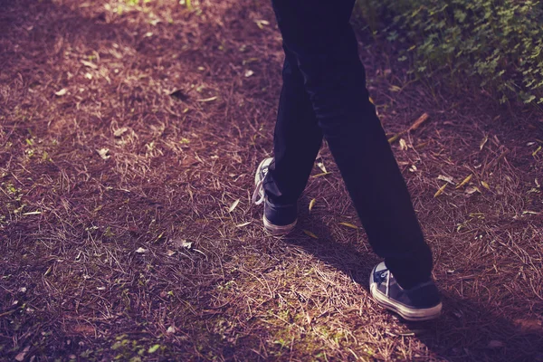 Pies en zapatillas de deporte caminando en el bosque. Tono vintage . —  Fotos de Stock