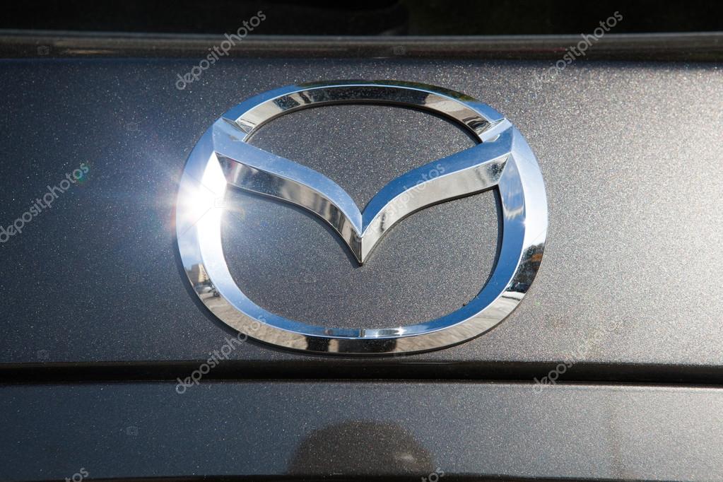 Close up detail of Mazda brand logo in a car. Mazda Motor Corporation, commonly referred to just as Mazda, is a Japanese automaker based in Fuchu, Aki District, Hiroshima Prefecture, Japan.