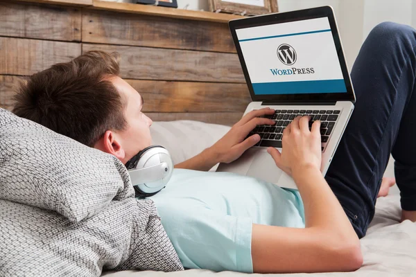 MALAGA, ESPANHA - NOVEMBRO 10, 2015: Wordpress logotipo da marca na tela do computador. Homem a escrever no teclado. WordPress é uma ferramenta de blogging livre e de código aberto e um sistema de gerenciamento de conteúdo (CMS ). — Fotografia de Stock