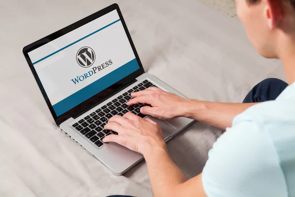 Malaga, İspanya - 10 Kasım 2015: Wordpress marka logosu bilgisayar ekranında. Klavyede yazarak adam. Bir ücretsiz ve açık kaynak bloglama aracı ve bir içerik yönetim sistemi (Cms WordPress olduğunu). Stok Fotoğraf