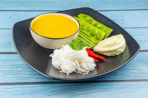 Top view Rice noodles in fish curry sauce with vegetables on a blue wood background