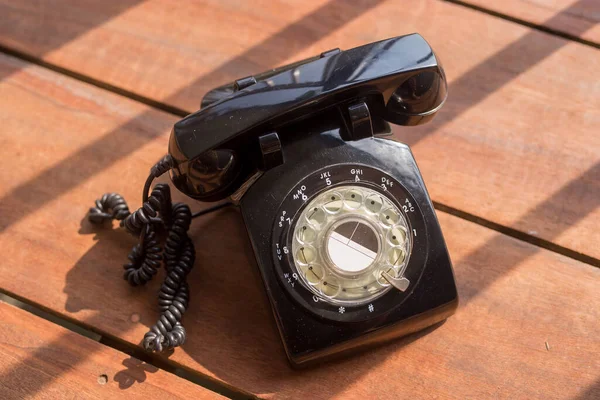 Ahşap arka planda klasik siyah telefon