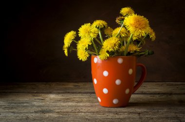 Antika ahşap masa üzerinde vazoda sarı dandelions demet