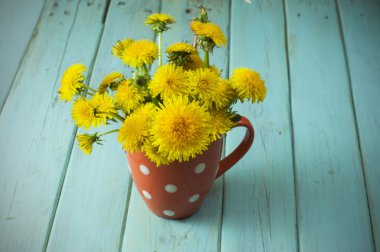 Antika ahşap masa üzerinde vazoda sarı dandelions demet