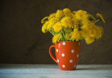 Antika ahşap masa üzerinde vazoda sarı dandelions demet