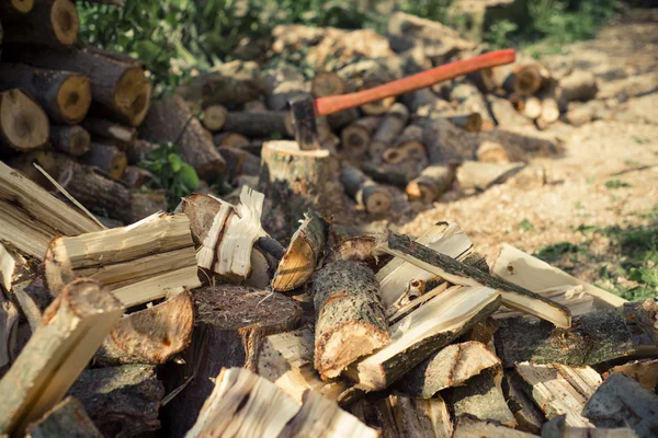 Топор застрял в пне на фоне рубленных дров — стоковое фото