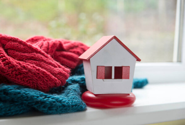 Шарф вокруг миниатюрного зеленого дома - концептуальный взгляд на защиту или изоляцию дома