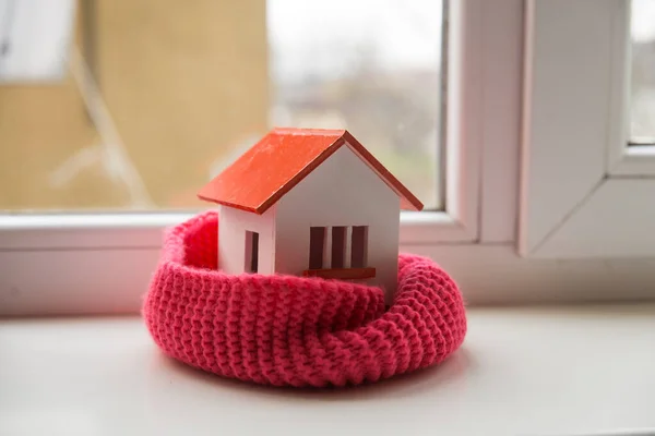 House in winter - heating system concept and cold snowy weather with model of a house wearing a knitted cap — Stock Photo, Image