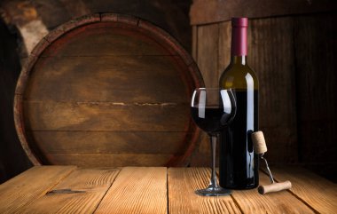 kırmızı şarap şişesi ve şarap kadehi yün fıçıda.