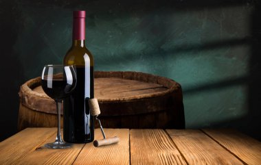 kırmızı şarap şişesi ve şarap kadehi yün fıçıda.