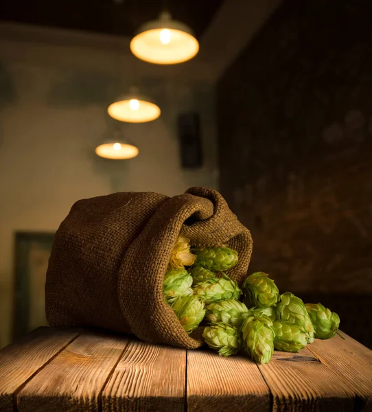 ビール醸造成分木製の割れた古いテーブルの上に袋と小麦の耳でホップ ビール醸造のコンセプト ホップコーンと小麦のクローズアップ ビンテージの背景にホップと小麦の葉の袋 — ストック写真