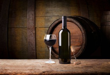 kırmızı şarap şişesi ve şarap kadehi yün fıçıda.