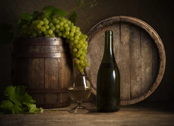 Vinho branco de vidro e uvas de ramo no fundo de madeira — Fotografia de Stock