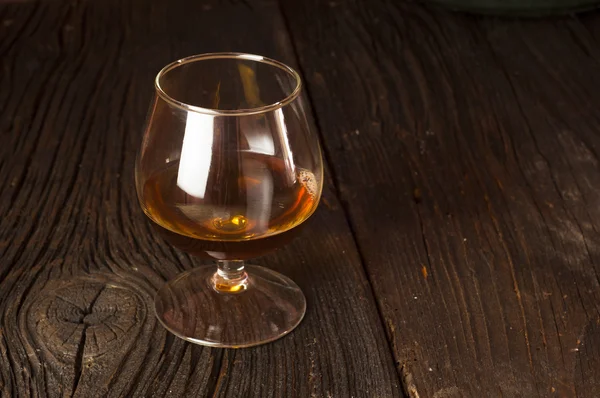 Glasses of brandy in cellar with old barrels — Stock Photo, Image